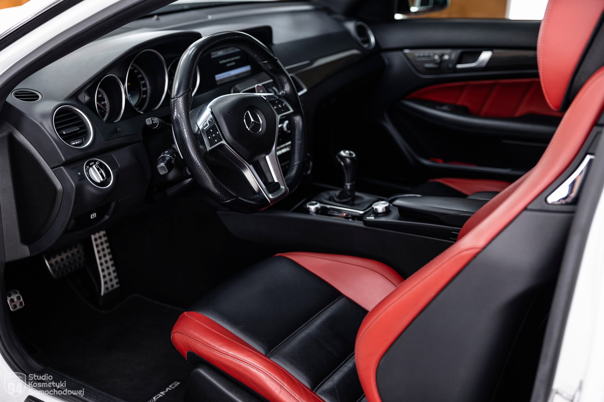 Wnętrze Mercedesa C63 AMG z czerwono-czarną skórzaną tapicerką, kierownicą i kokpitem